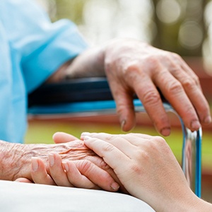 Doctor holding elderly patient 's hand in a wheelchair.